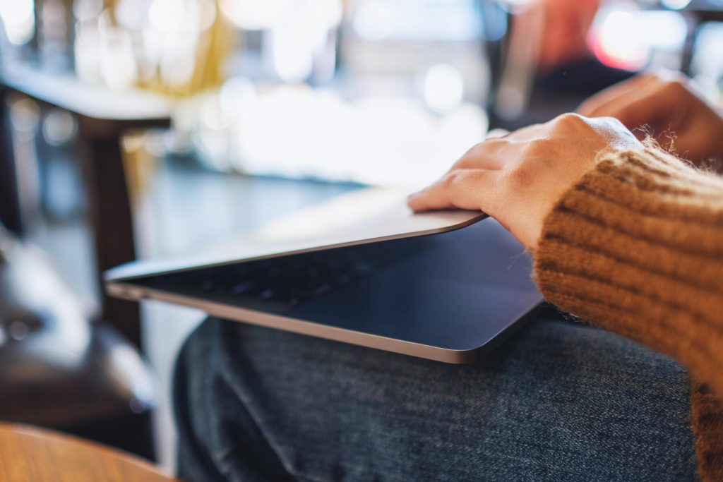 person shutting lid of laptop